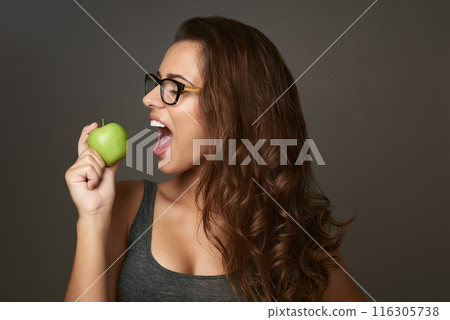 Studio background, bite and apple with woman for eating, vitamin c and mineral for nutrition. Female nutritionist, organic fruit and healthy diet for detox, weight loss or product benefits with pride 116305738