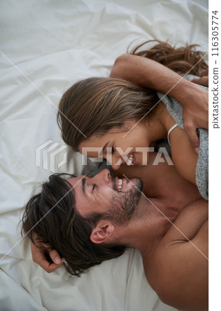 Couple, cuddle and smile in bed for morning romance, love and bonding on weekend. Relationship, man and woman laying together in home for comfort, relax or care and playing with partner from above Couple, cuddle and smile in bed for morning romance, love and bonding on weekend. Relationship, man and woman laying together in home for comfort, relax or care and playing with partner from above 116305774