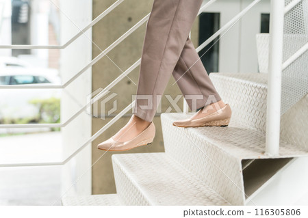 The feet of a businesswoman descending the stairs 116305806