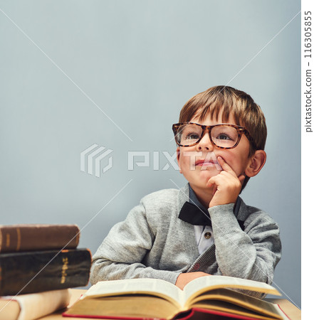 Boy, child and books in studio for learning, glasses and education with mock up space by blue background. Kid, textbook and vision for future with studying, scholarship and development at academy 116305855