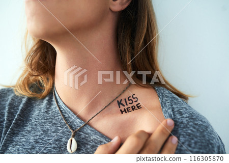 Person, words or tattoo design on neck for unique creative style in studio on blue background. Identity, results and kiss here text with ink on skin for creativity, closeup or artistic expression 116305870