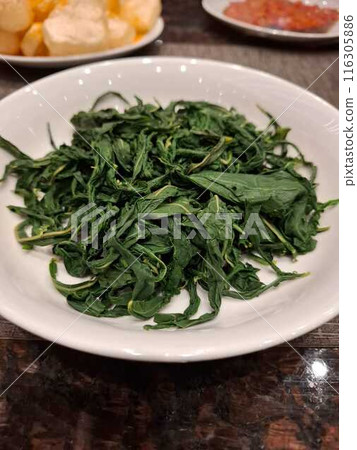 Boiled cassava leaf vegetables are served as a side dish for rice 116305886