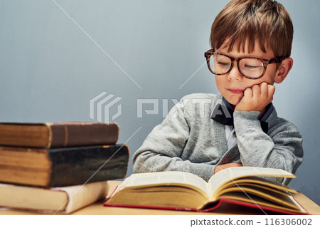 Boy, child and books in studio for reading, glasses and education with mock up space by blue background. Kid, textbook and education for future with learning, scholarship and development at academy Boy, child and books in studio for reading, glasses and education with mock up space by blue background. Kid, textbook and education for future with learning, scholarship and development at academy 116306002