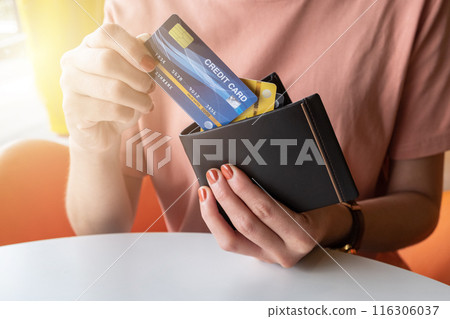 Cropped shot view of female hands picking credit cards from her wallet. Cropped shot view of female hands picking credit cards from her wallet. 116306037