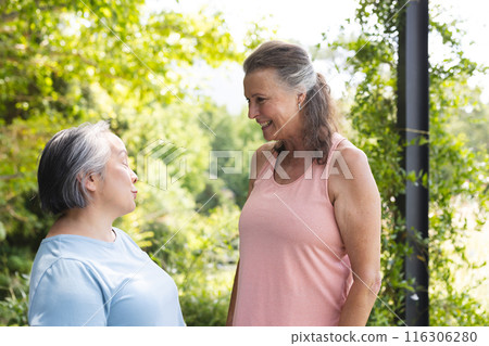 Outdoors, two senior female friends are chatting in casual tops 116306280