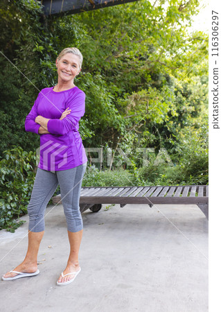 A senior Caucasian female standing outdoors, wearing purple top, copy space 116306297