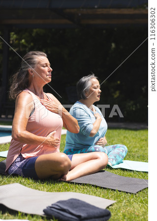 Diverse senior female friends practicing yoga outdoors Diverse senior female friends practicing yoga outdoors 116306302
