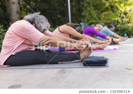 Outdoors, diverse senior female friends stretching on yoga mats Outdoors, diverse senior female friends stretching on yoga mats 116306314