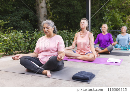 Diverse senior female friends practicing yoga outdoors Diverse senior female friends practicing yoga outdoors 116306315