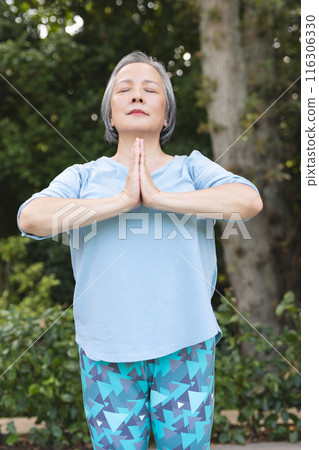 A senior Asian female practicing yoga outdoors with blue background A senior Asian female practicing yoga outdoors with blue background 116306330