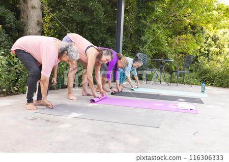 Outdoors, diverse senior female friends rolling out yoga mats 116306333