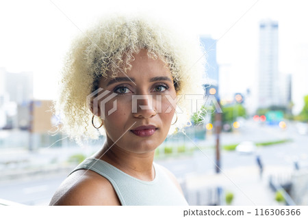Young biracial woman with blonde curls and brown eyes looks ahead in modern office Young biracial woman with blonde curls and brown eyes looks ahead in modern office 116306366