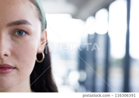 In modern office, young Caucasian female wearing green headband standing, copy space 116306391