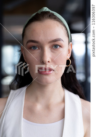 In modern office, young Caucasian female wearing hoop earrings looking forward 116306397