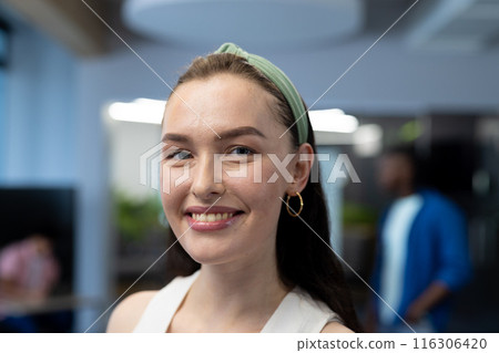 In modern office, a Caucasian female with a green headband, smiling 116306420