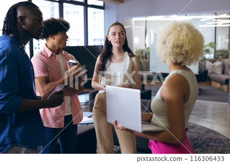 In modern office, diverse young team discussing with laptops and coffee In modern office, diverse young team discussing with laptops and coffee 116306433