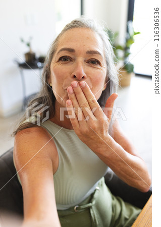 At home, Caucasian mature woman blowing kiss during video call 116306536