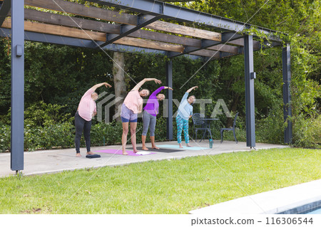 Diverse senior female friends stretching, doing yoga in green park, copy space Diverse senior female friends stretching, doing yoga in green park, copy space 116306544