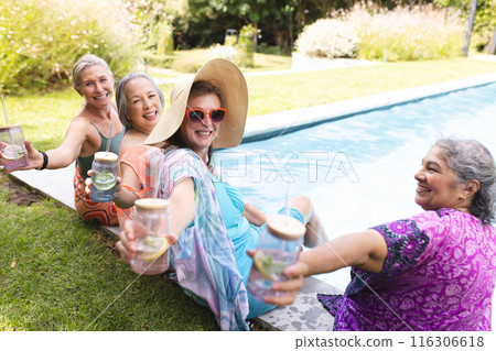 Outdoor gathering of diverse senior female friends enjoying drinks by pool Outdoor gathering of diverse senior female friends enjoying drinks by pool 116306618