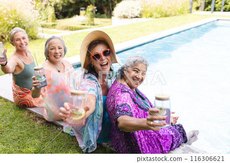 Diverse senior female friends laughing outdoors by pool, copy space Diverse senior female friends laughing outdoors by pool, copy space 116306621