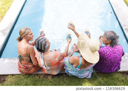 Diverse senior female friends relaxing outdoors by pool, copy space 116306629