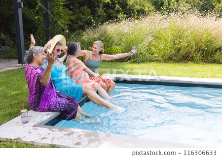 Diverse senior female friends laughing outdoors, wearing colorful attire, copy space 116306633