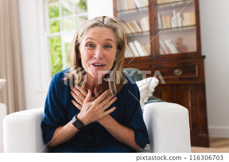 A caucasian senior female sitting during video call at home, looking surprised A caucasian senior female sitting during video call at home, looking surprised 116306703