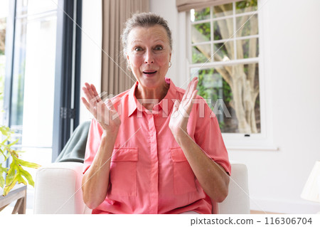 A senior Caucasian woman with short gray hair clapping hands at home, on video call 116306704