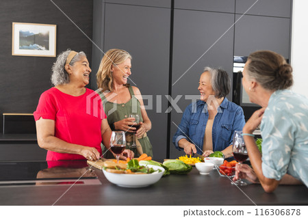 Diverse senior female friends enjoying meal together at home 116306878
