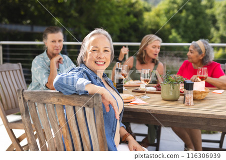 Diverse senior female friends enjoying meal outdoors, sharing stories Diverse senior female friends enjoying meal outdoors, sharing stories 116306939