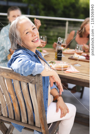 Diverse senior female friends enjoying meal outdoors 116306940