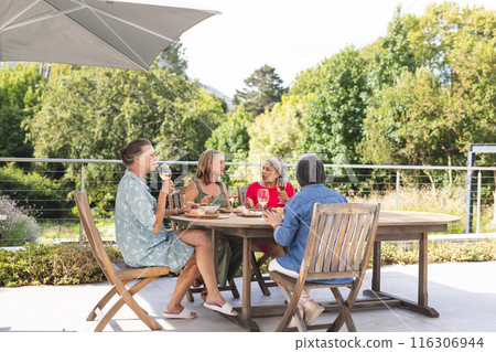 Diverse senior female friends enjoying meal outdoors Diverse senior female friends enjoying meal outdoors 116306944