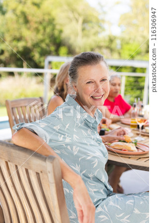 Diverse senior female friends enjoying meal outdoors Diverse senior female friends enjoying meal outdoors 116306947