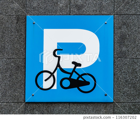 A bicycle parking sign on the wall of a building near the station 116307202