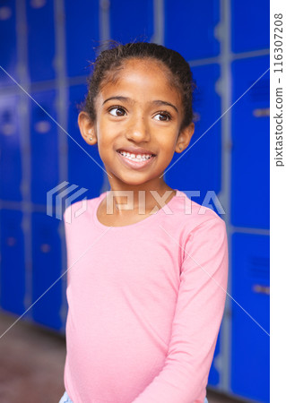 In school, biracial young girl standing by blue lockers, looking away In school, biracial young girl standing by blue lockers, looking away 116307208