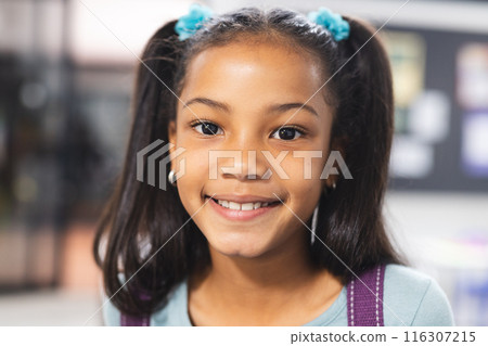 In school, young African American girl wearing a backpack standing 116307215