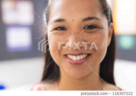 A young biracial female teacher with freckles is smiling in a classroom A young biracial female teacher with freckles is smiling in a classroom 116307222