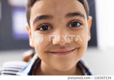 In school, young biracial boy with short dark hair and brown eyes is smiling in the classroom In school, young biracial boy with short dark hair and brown eyes is smiling in the classroom 116307234