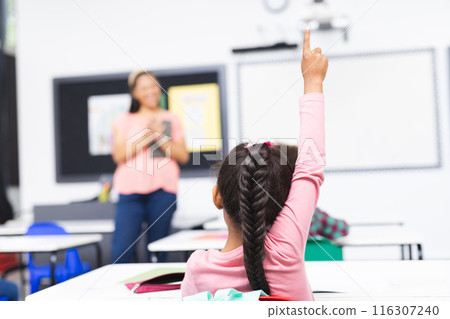 In school, in classroom, biracial young woman teaching, young girl raising hand 116307240