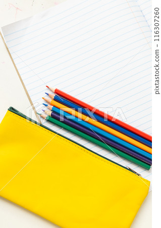 In school, colored pencils lying on top of yellow pencil case with copy space in the classroom 116307260