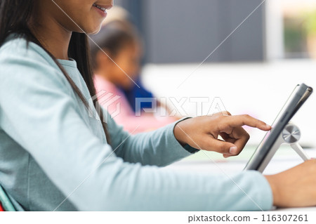 In school, in a classroom, a biracial female teacher and her daughters are using tablets In school, in a classroom, a biracial female teacher and her daughters are using tablets 116307261