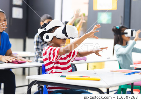 In school, diverse students wearing virtual reality headsets are reaching out in the classroom 116307268