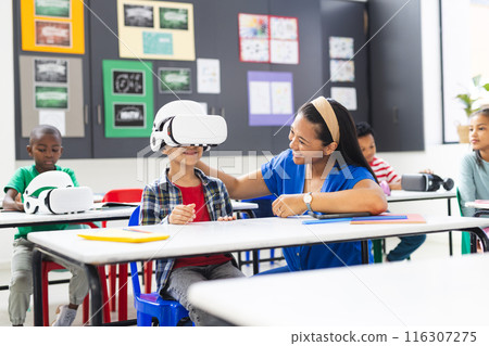 A middle-aged biracial teacher assists young biracial boy with a VR headset A middle-aged biracial teacher assists young biracial boy with a VR headset 116307275