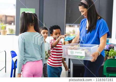In school, a biracial female teacher is showing recycling to students 116307281