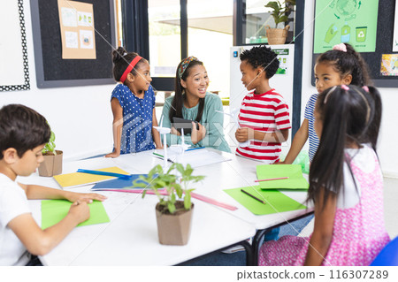 In school, middle-aged Asian woman teaching sustainability to diverse children in classroom 116307289