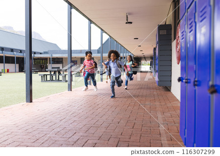 In school, diverse children are running in the corridor with copy space outdoors 116307299