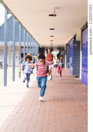 In school, diverse children are running down the hallway with copy space outdoors 116307301