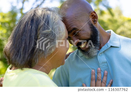 A diverse senior couple laughing outdoors, sporting grey hair A diverse senior couple laughing outdoors, sporting grey hair 116307762