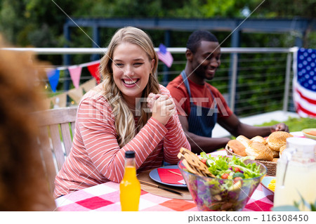 Happy diverse group of friends talking and having dinner at balcony with flags of usa Happy diverse group of friends talking and having dinner at balcony with flags of usa 116308450
