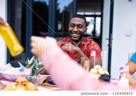 Happy diverse group of friends talking and having dinner at balcony with flags of usa Happy diverse group of friends talking and having dinner at balcony with flags of usa 116308453